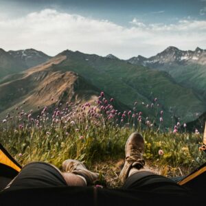 person lying inside tent and overlooking mountain